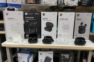 Display showcasing various wireless earbuds models, including AirBuds, Tune Beans, Dots, Airflow, and Beat, with packaging and charging cases.