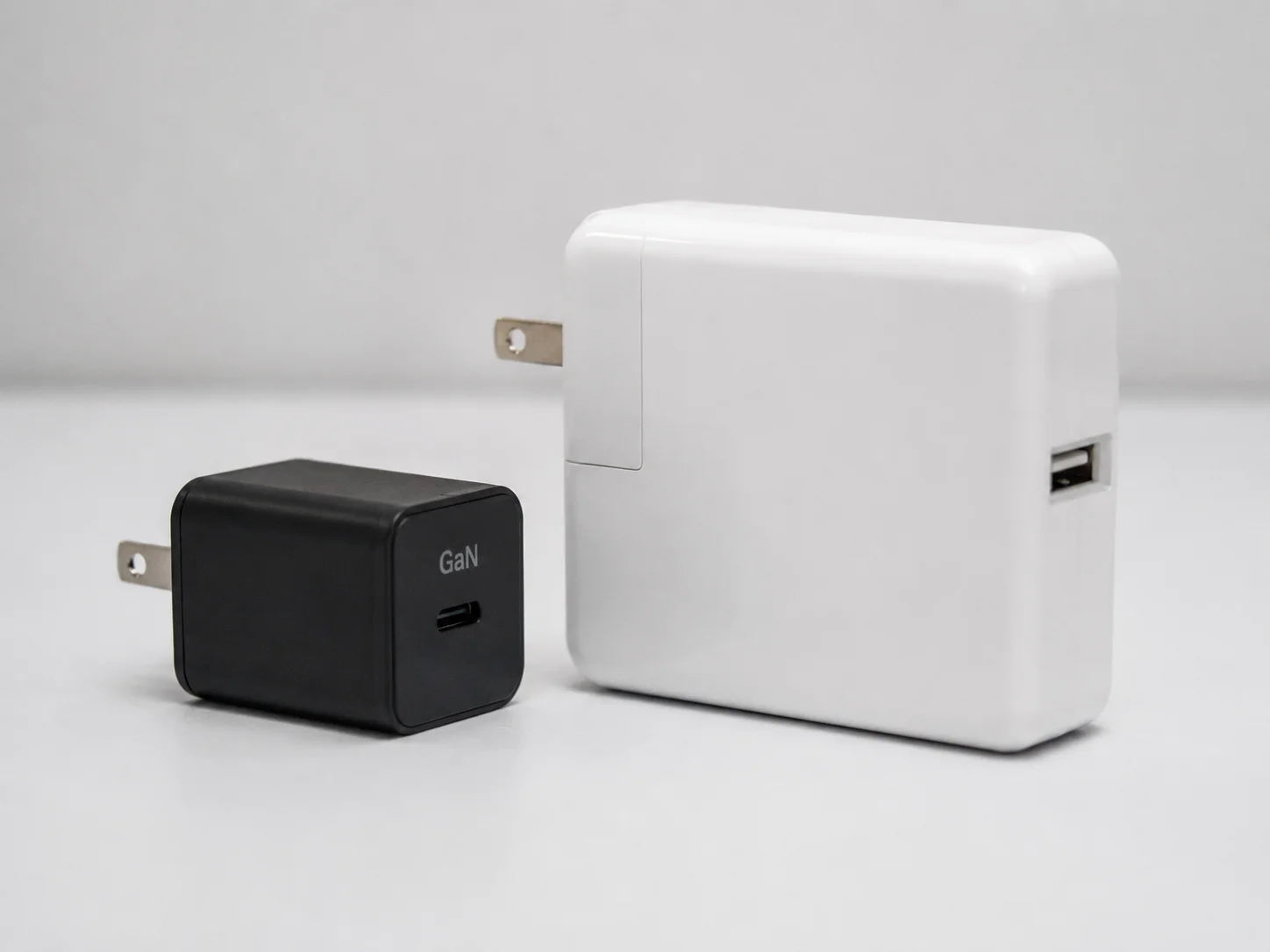 A small GaN charger next to a larger, older silicon charger