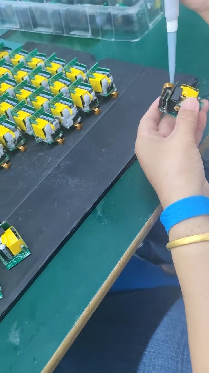 Protection material being applied to charger PCBA units at an assembly bench