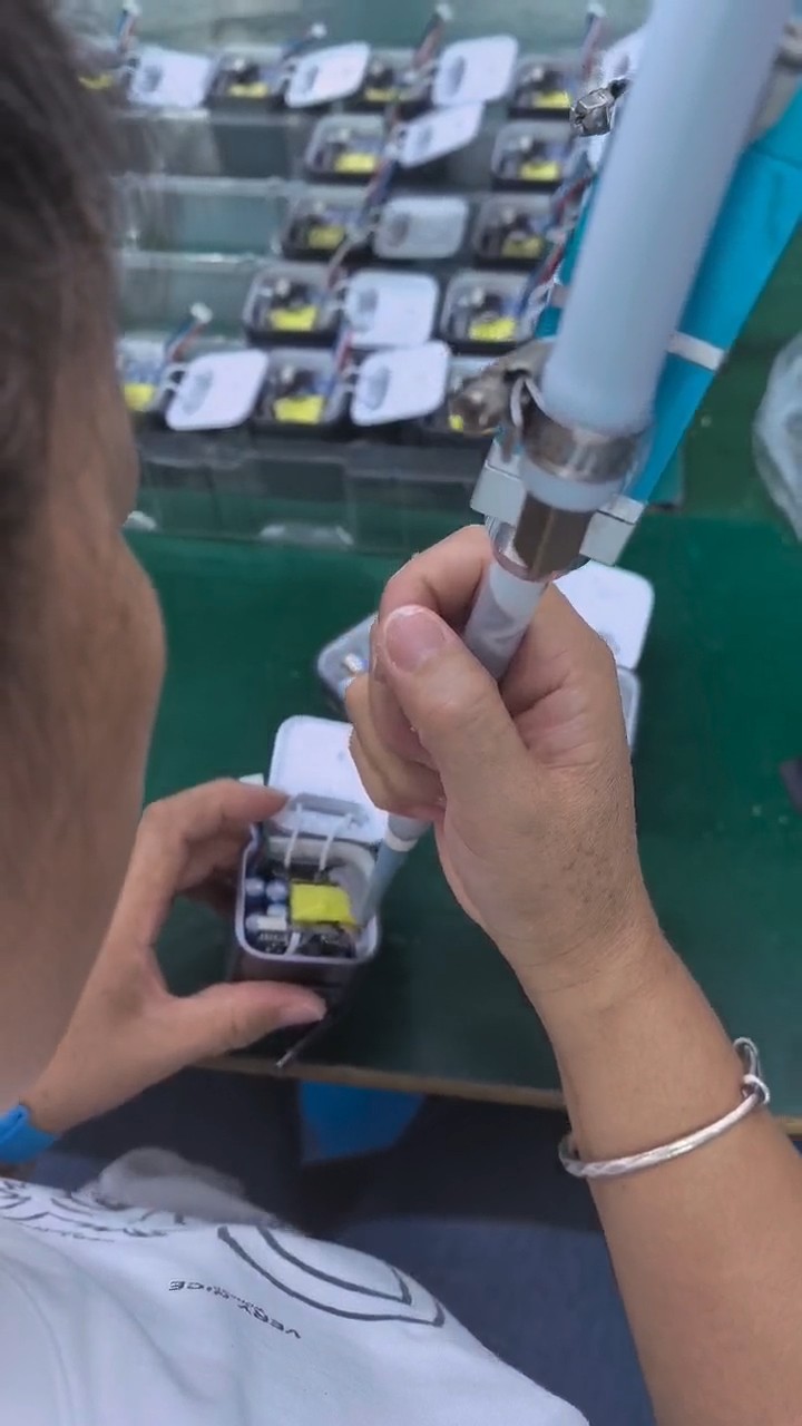 Thermal compound being dispensed into charger housings on a production bench